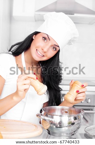beautiful girl cooking in the kitchen at home and adding salt and pepper