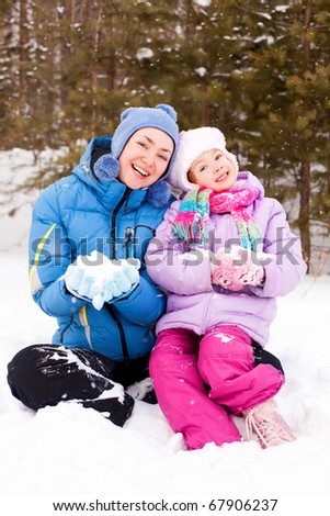 happy family; young mother and her daughter having fun in the winter park (focus on the woman)