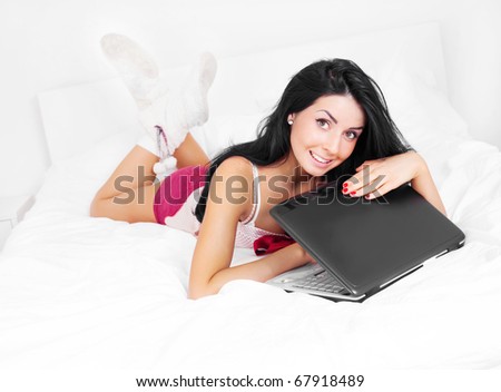 happy brunette girl with a laptop on the bed at home