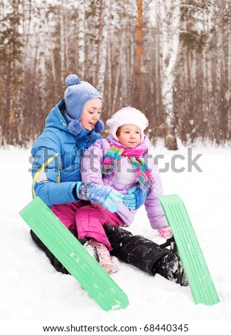 happy family; young mother and her daughter skiing and having fun in the winter park (focus on the child)