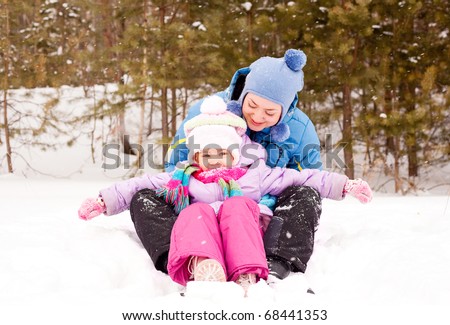 happy family; young mother and her daughter having fun in the winter park (focus on the child)