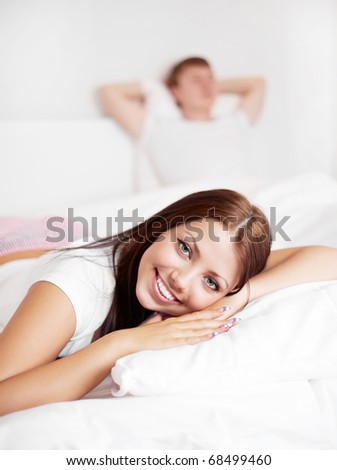 happy young woman and  sleeping man on the bed at home (focus on the woman)
