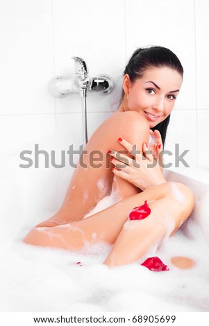 beautiful young brunette woman taking a relaxing bath with foam