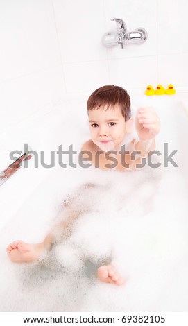 cute four year old boy taking a relaxing bath with foam