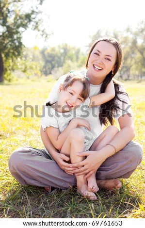 beautiful young mother and her daughter in the park on a sunny autumn day