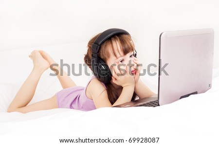 five year old girl with a laptop on the bed at home