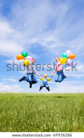 happy jumping family with balloons outdoor on a summer day