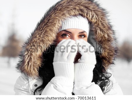 pretty young brunette woman wearing warm winter clothes outdoor, closing her face with hands