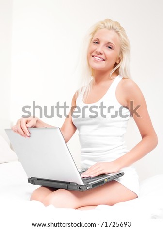 happy blond girl with a laptop on the bed at home