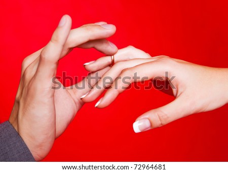 hands of a bride and a groom, man putting a wedding ring on the finger of his bride