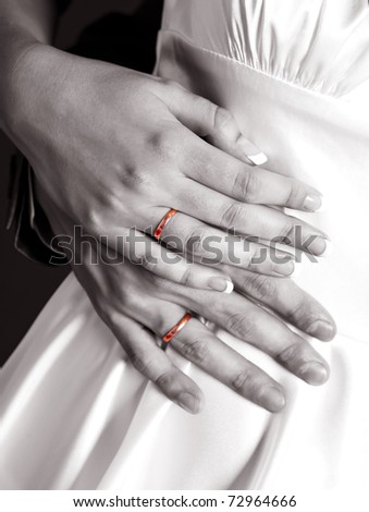 block and white picture of the hands of a bride and a groom with golden wedding rings (accent on the golden rings)