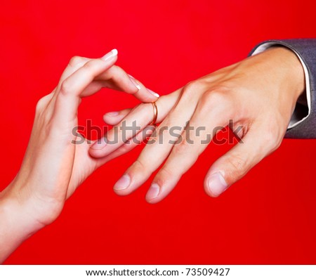 hands of a bride and a groom, woman putting a wedding ring on the finger of her groom