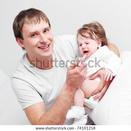 young father feeding his his six months old daughter on the bed at home