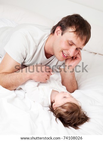 young father with his six months old daughter on the bed at home (focus on the man)