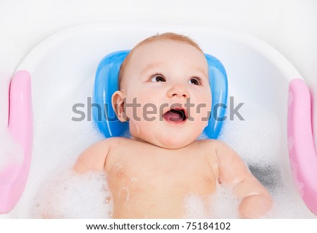cute six months old baby taking a relaxing bath with foam