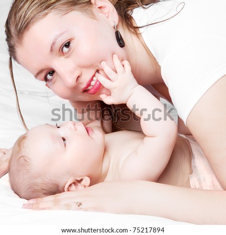 young  mother and her six months old baby on the bed at home