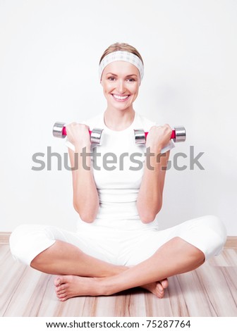 beautiful young woman working out with two dumbbells at home