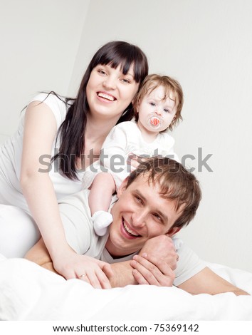 happy family, mother ,father and their baby on the bed at home  (focus on the woman)