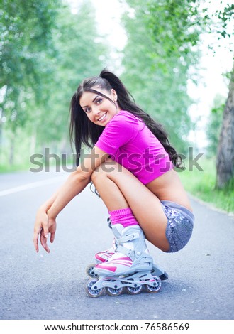 happy young brunette woman on roller skates in the park