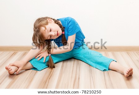 beautiful five year old girl stretching the muscles of her back and legs  at home