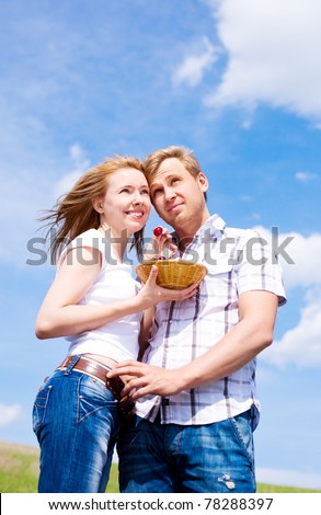 happy young couple having a picnic outdoor on a summer day, a girl feeding her boyfriend with cherries