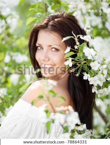 beautiful young brunette woman standing near the apple tree