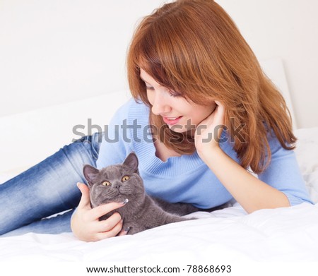 pretty young woman with her cat on the bed at home