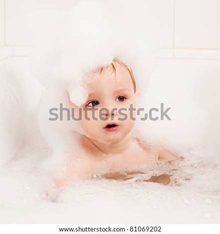cute one year old boy taking a  bath with foam