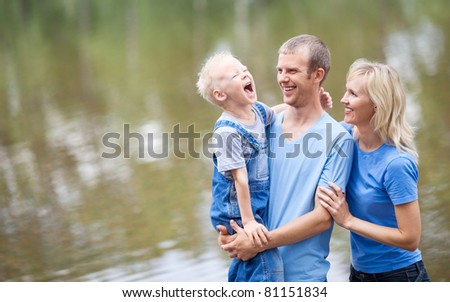 happy young family  near the lake outdoor on a summer day (focus on the woman)