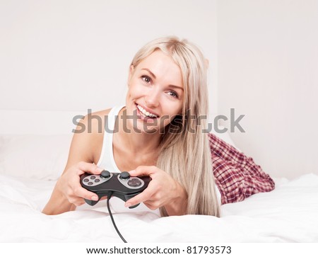 beautiful young blond woman playing computer games on the bed at home