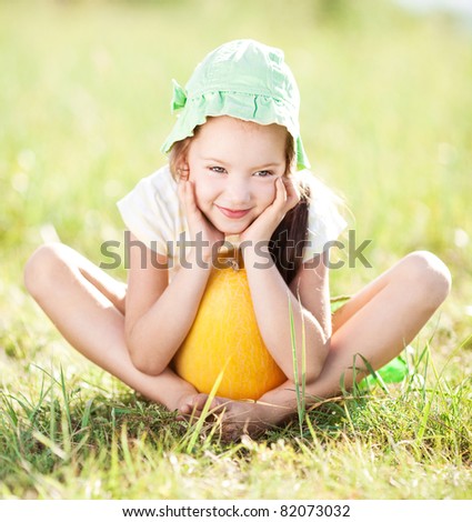 cute happy  little girl with melon on the grass in summertime