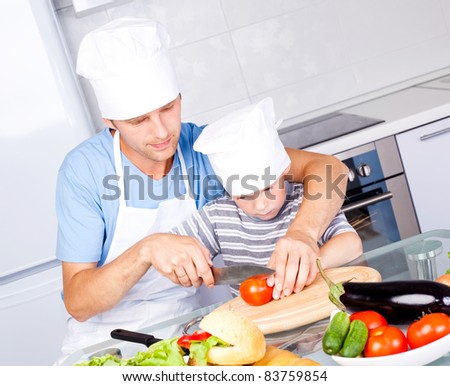 young father and his five year old son cook together in the kitchen at home