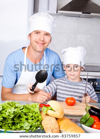 young father and his five year old son cook together in the kitchen at home