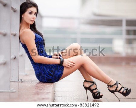 beautiful young brunette woman wearing a blue mini dress in the street