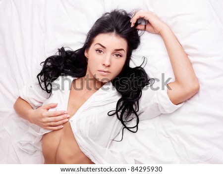 sexy young brunette woman wearing a white shirt on the bed at home