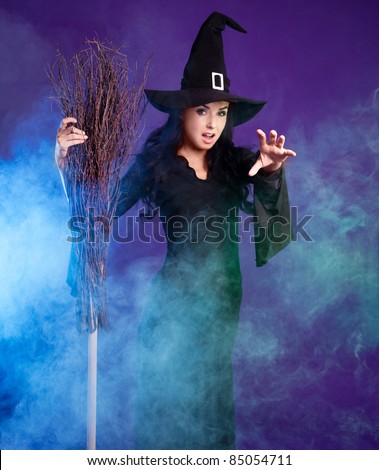 angry sexy young brunette witch with a broom and foam around her, isolated against white background