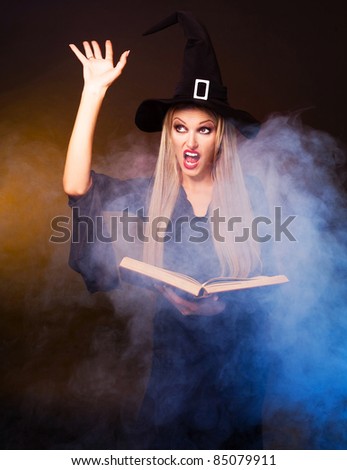 angry  blond witch with a book and her hands and clouds of blue smoke around her conjuring, against black and yellow background