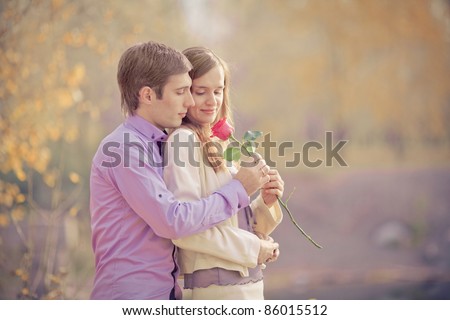 low contrast image of a happy young couple spending time outdoor in the autumn park (focus on the man)