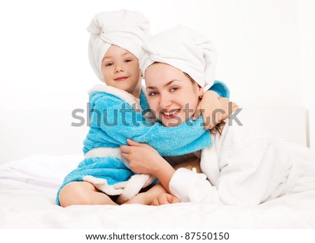 beautiful young mother and her five year old daughter on the bed at home