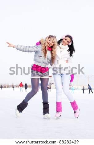 two beautiful girls ice skating outdoor on a warm winter day