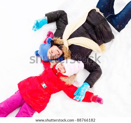happy  family; mother and daughter making snow angels outdoor on a winter day