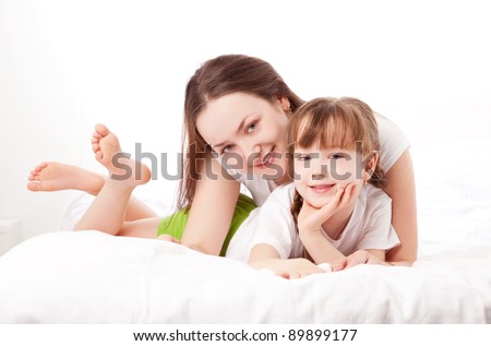 beautiful young mother and her five year old daughter on the bed at home