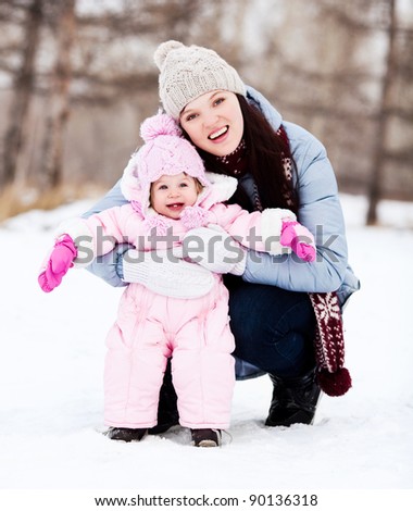 happy young mother with her daughter spending time outdoor in the winter park