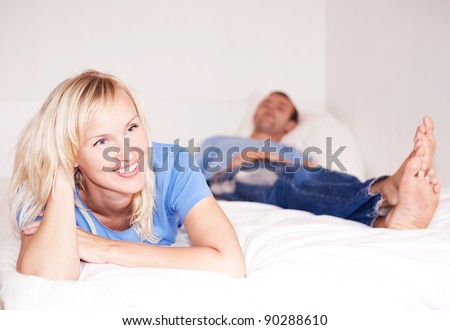 happy young woman and  sleeping man in bed at home (focus on the woman)