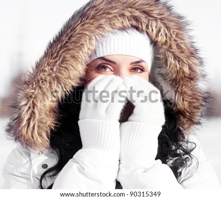 pretty young brunette woman wearing warm winter clothes, covering her face with hands, outdoor in the park