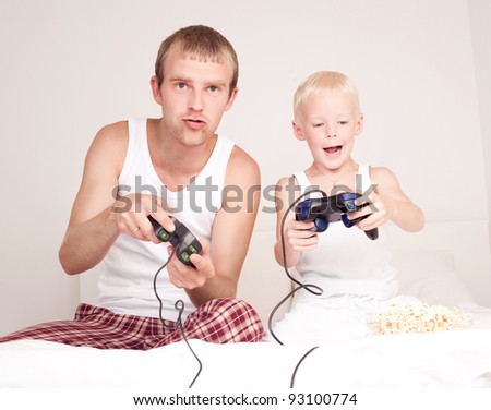 happy family;  father and his little son playing computer games on the bed at home