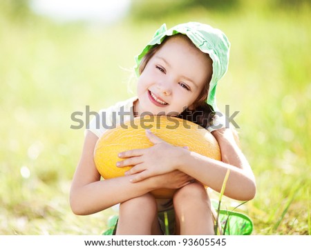 cute happy  little girl with melon on the grass in summertime