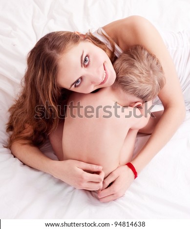 happy young mother and her two year old son in bed at home (focus on the woman)