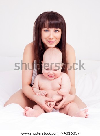 happy young mother and her one year old daughter in bed at home