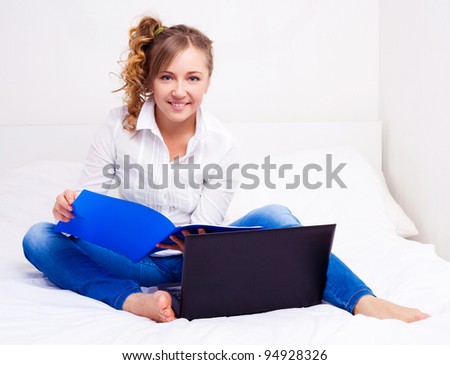 pretty happy student with the laptop in bed at home